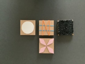 vier quadratische Blöcke auf denen geometrische eingeschnitzte Stempel zu sehen sind.