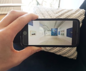Foto: Hand mit Smartphone, das eine Ausstellungsansicht von Moebius zeigt 