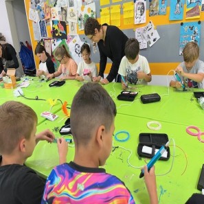 Kinder sitzen an einem Tisch und basteln