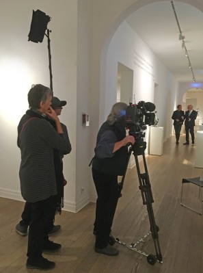 The image shows people shooting with cameras in the museum.