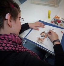 Foto: Ein Mädchen mit Hörgerät im Kreativkurs