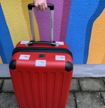 Ein roter Koffer vor einer bunten Wand