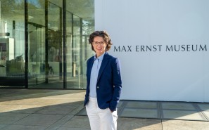 Museumsdirektorin Madeleine Frey steht lächelnd vor dem Museumseingang.